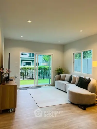 Modern living room with stylish furniture and garden view through large windows.