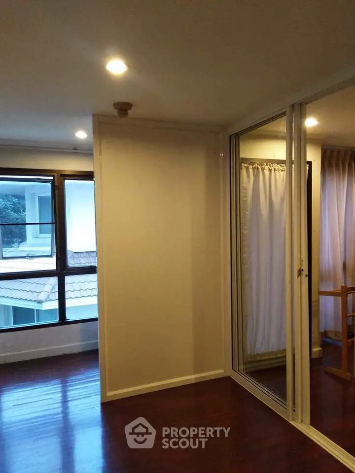 Spacious room with large windows and wooden flooring, perfect for customization.
