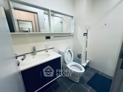 Modern bathroom with sleek fixtures and large mirror in contemporary home.