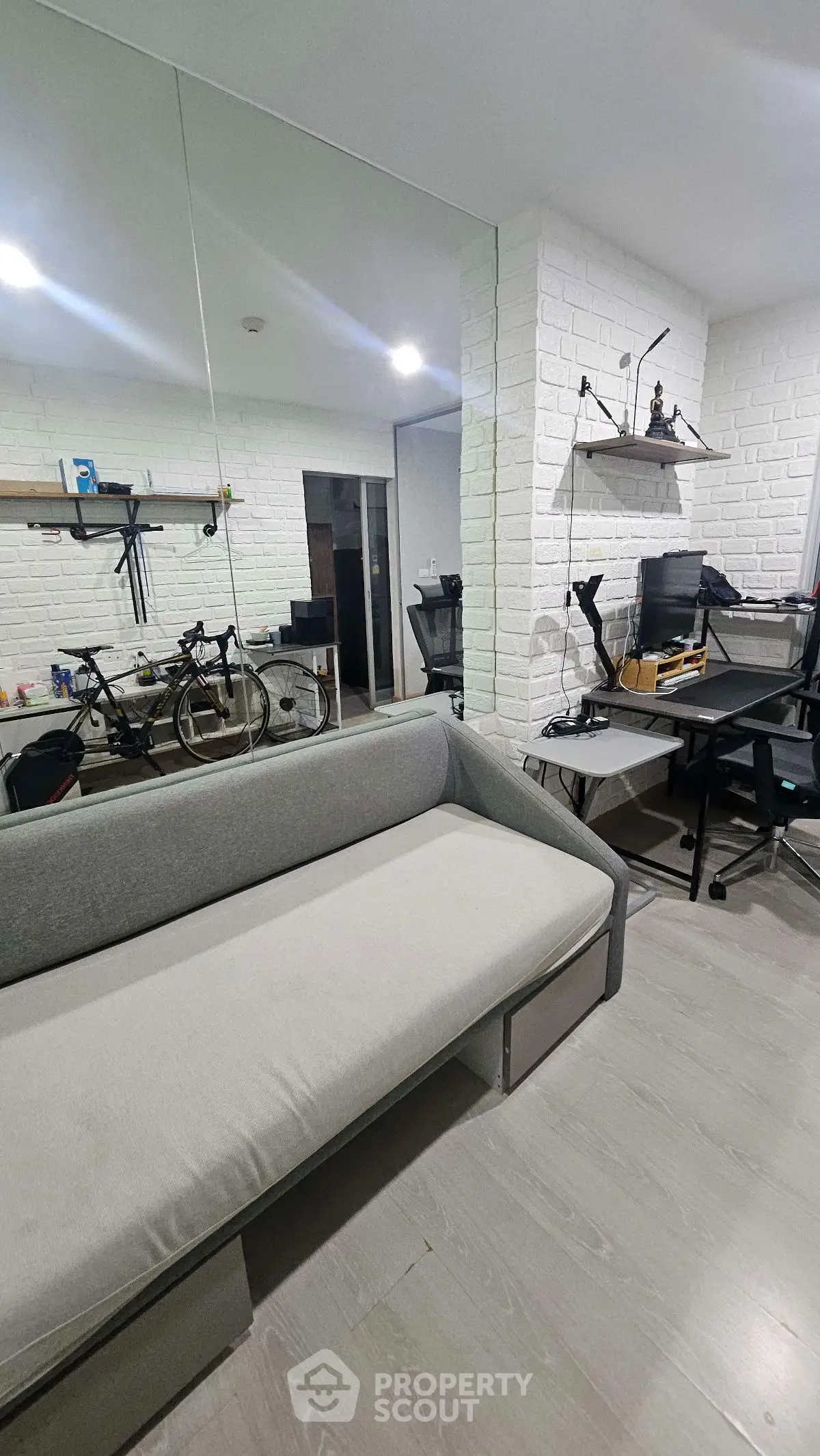 Modern study room with sleek sofa and mirrored wall, perfect for productivity and relaxation.