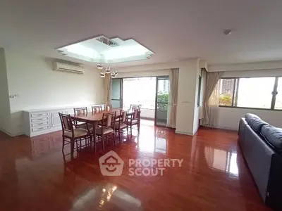 Spacious living room with elegant dining area and large windows offering natural light.