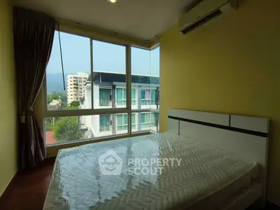 Bright bedroom with large windows offering a scenic view, featuring a modern bed and air conditioning.