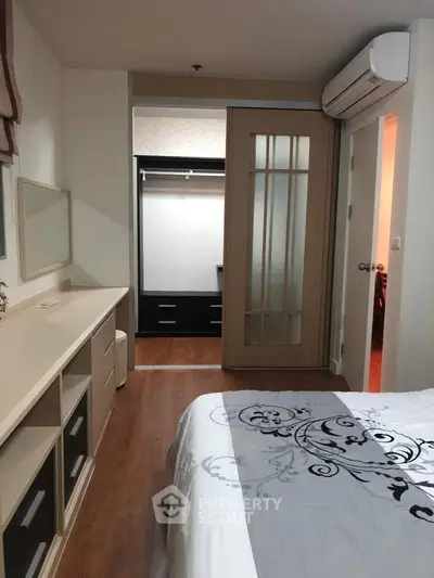 Cozy bedroom with sliding door leading to a walk-in closet, featuring modern decor and wooden flooring.