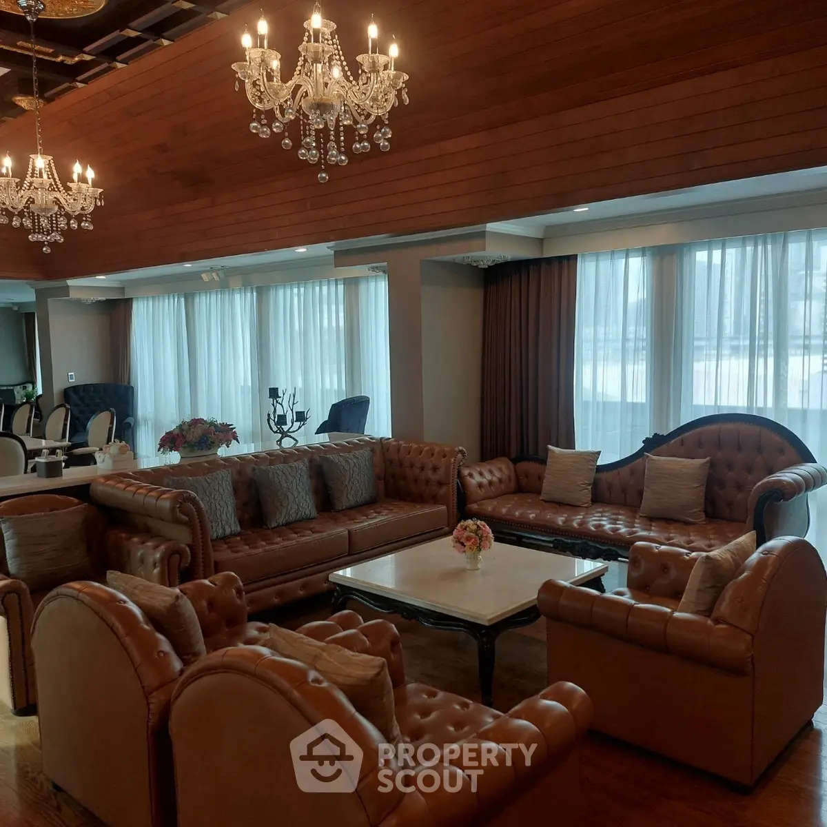 Luxurious living room with elegant chandeliers and plush leather sofas in a sophisticated setting.