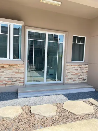 Charming exterior with sliding glass doors and stone accents, perfect for modern living.