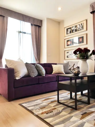 Elegant living room with plush purple sofa, stylish decor, and natural light.