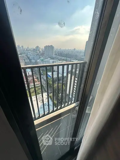 Stunning cityscape view from high-rise balcony with glass door and railing.