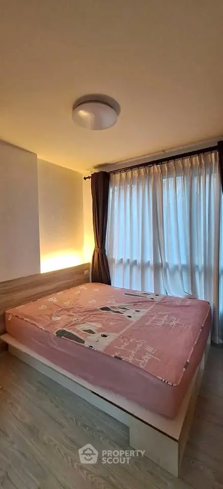 Cozy bedroom with large window and stylish lighting, perfect for relaxation and comfort.