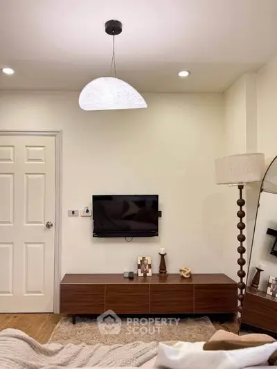 Modern bedroom with stylish decor, featuring a sleek TV setup and elegant lighting.