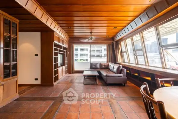 Spacious living room with wooden ceiling and large windows offering city views.