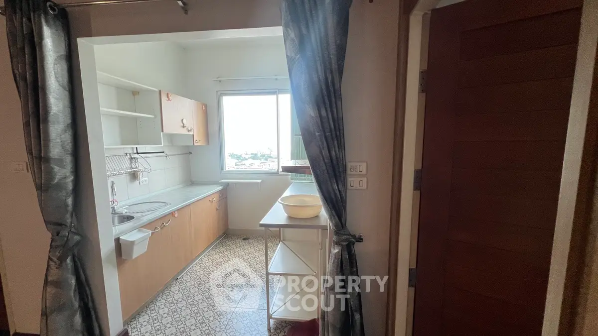 Cozy kitchen with natural light and open shelving, perfect for compact living.