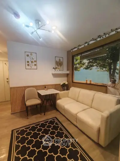 Charming living room with cozy seating and large window offering scenic views, perfect for relaxation.