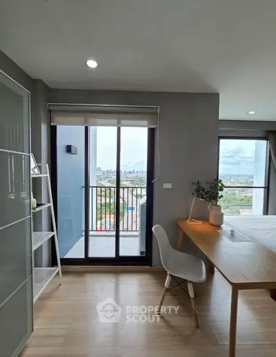 Modern bedroom with balcony and city view, featuring sleek furniture and natural light.