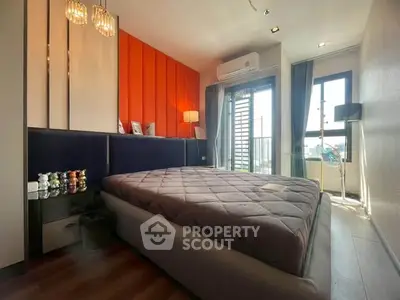 Modern bedroom with vibrant orange accent wall and balcony access