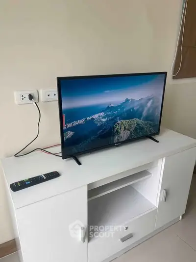 Modern living room with sleek TV setup on white cabinet, perfect for entertainment.
