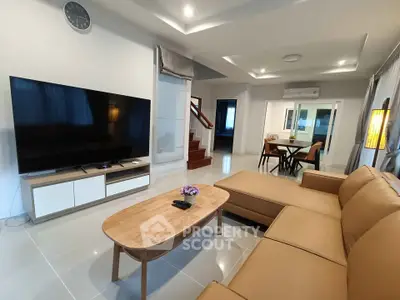 Spacious modern living room with large TV and comfortable seating in a stylish home.