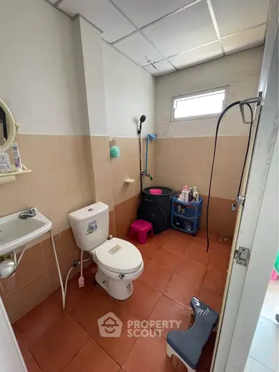 Compact bathroom with shower, toilet, and sink, featuring tiled walls and floor, ideal for efficient space use.