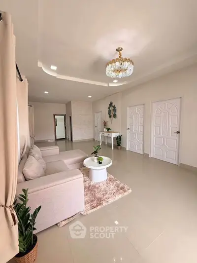 Spacious living room with elegant chandelier and modern decor in a stylish apartment.