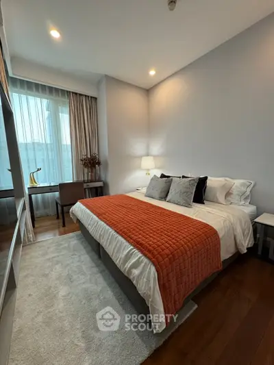 Modern bedroom with stylish decor and large window offering natural light