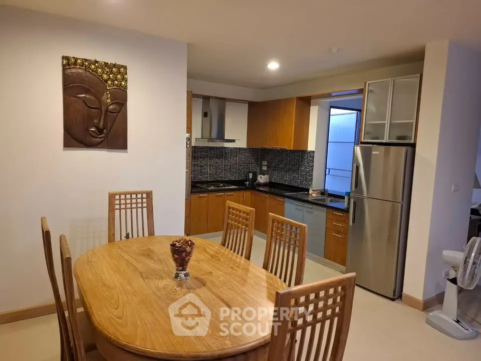 Modern kitchen with wooden dining set and stainless steel fridge in cozy apartment.