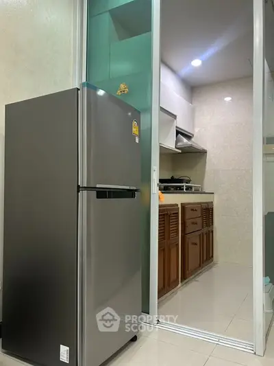 Modern kitchen with stainless steel fridge and sleek cabinetry in compact layout.
