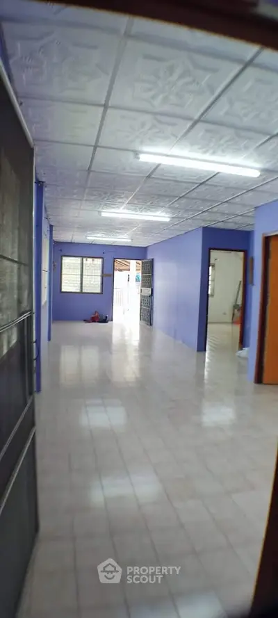 Spacious open-plan interior with tiled flooring and blue walls, ideal for versatile living arrangements.