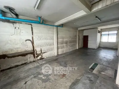 Spacious industrial-style room with concrete walls and exposed pipes, ideal for creative workspace or storage.