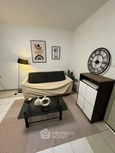 Cozy living room with modern decor, featuring a stylish sofa, chic wall art, and a sleek glass coffee table.