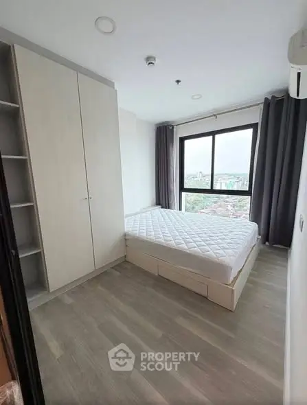 Modern bedroom with large window and built-in wardrobe offering city views.