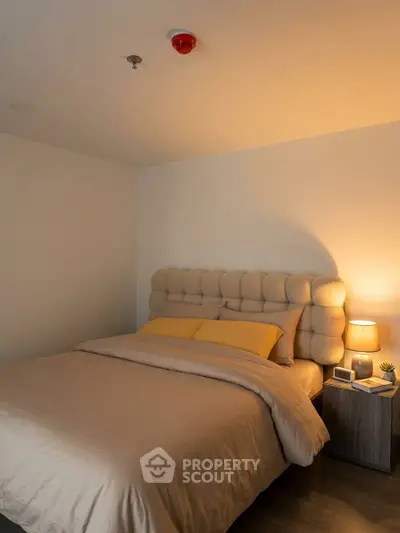 Cozy bedroom with plush headboard and warm lighting, perfect for relaxation.