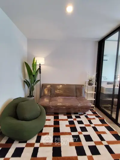 Modern living room with stylish furniture and geometric rug in a cozy apartment setting.