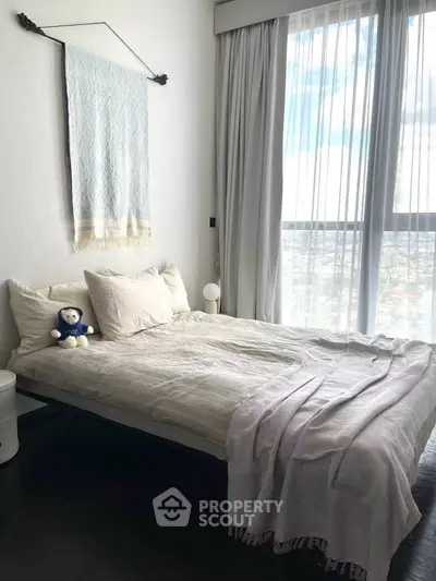 Cozy bedroom with large window and stylish decor, offering a serene and inviting atmosphere.