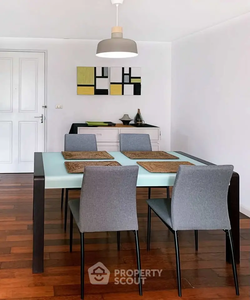 Modern dining room with stylish table and chairs, wooden flooring, and contemporary wall art.