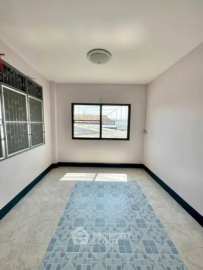 Bright room with large window and tiled floor, perfect for versatile use in a modern home.