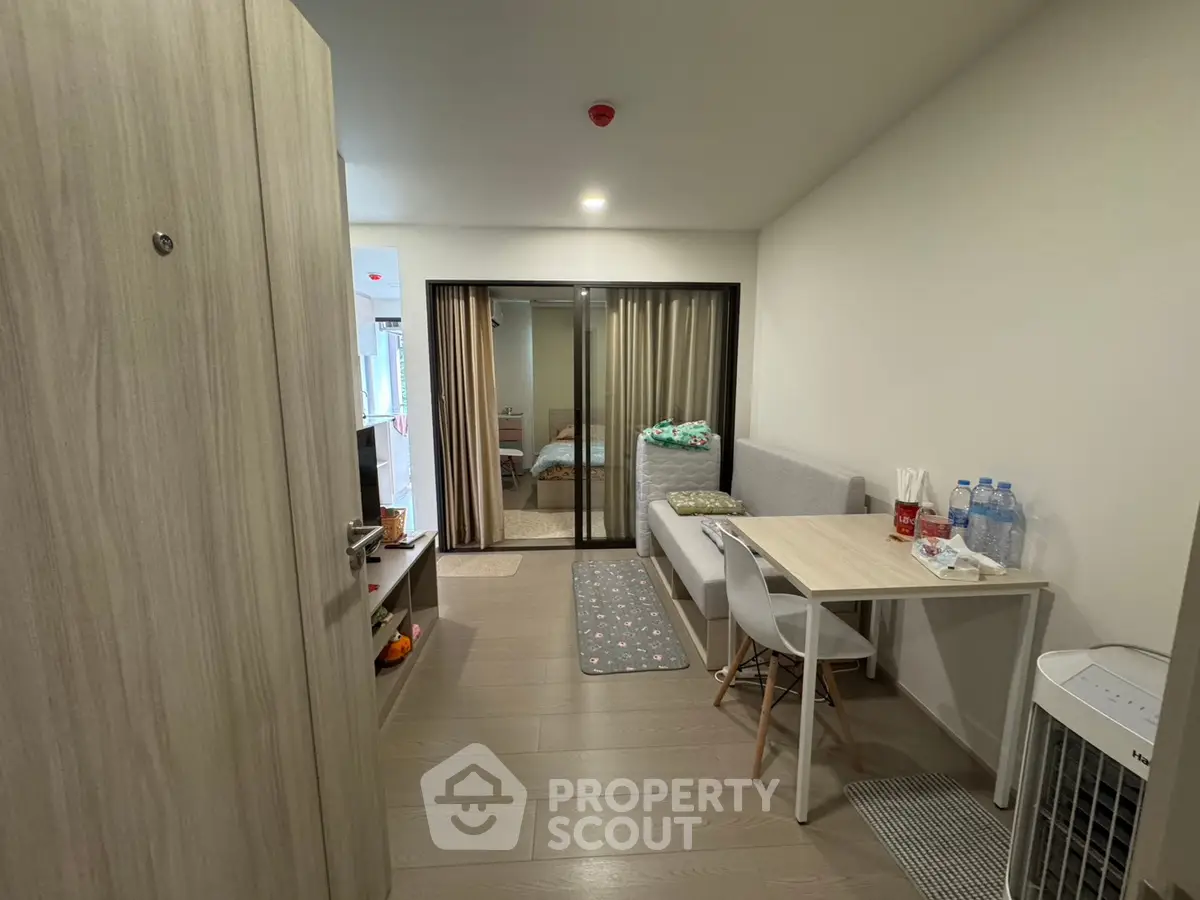 Modern apartment interior with open layout, featuring a cozy dining area and view into the bedroom.