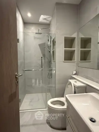 Modern bathroom with glass shower and sleek fixtures in a contemporary apartment.