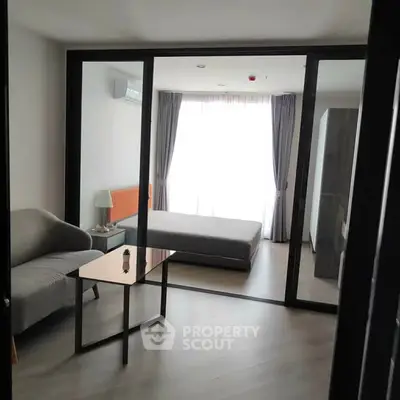 Modern studio apartment with glass partition, cozy living area, and natural light.