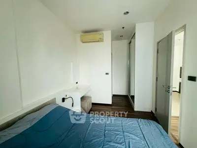 Modern bedroom with sleek design, featuring a cozy bed, air conditioning, and stylish wooden flooring.
