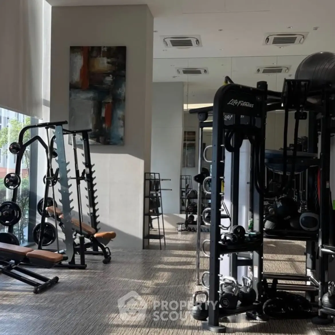 Modern gym with state-of-the-art fitness equipment and stylish decor in a luxury residential building.