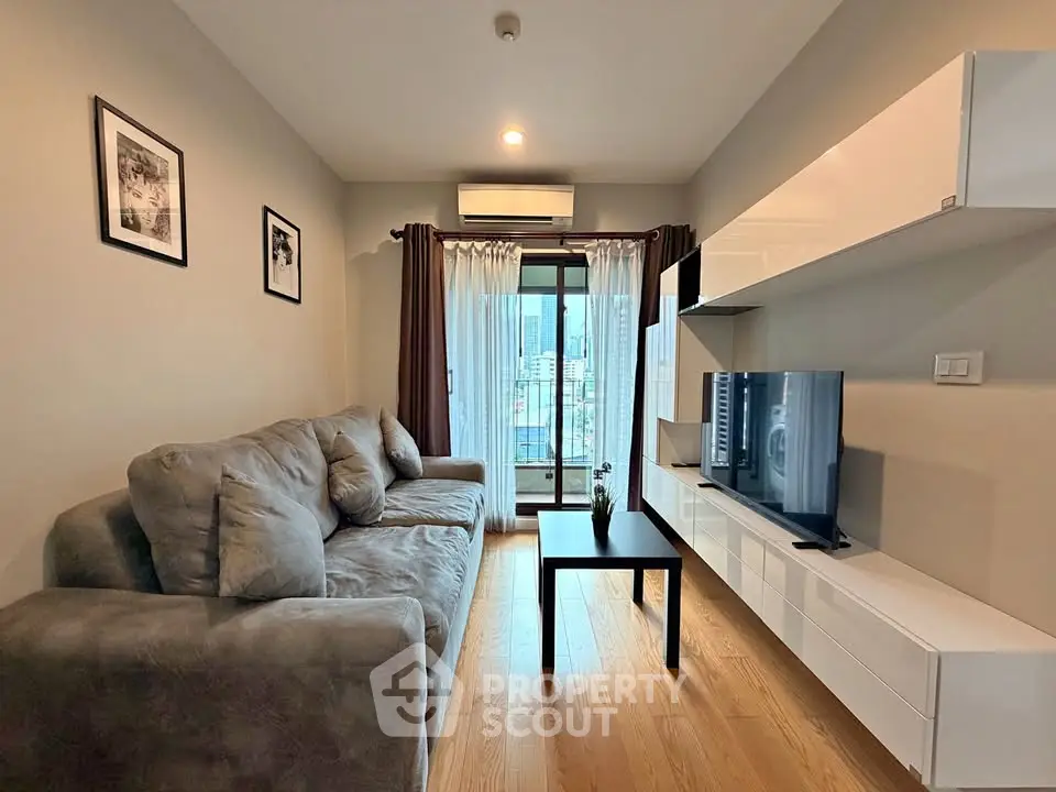Modern living room with cozy sofa, wall-mounted TV, and city view balcony.