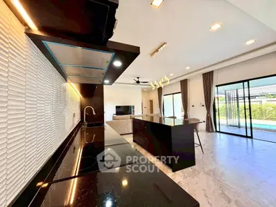 Luxurious open-layout kitchen and living room with pool view, modern appliances, and elegant design.