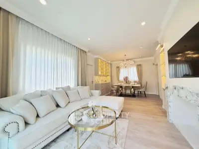 Luxurious living room with elegant decor and open dining area, featuring plush seating and modern lighting.