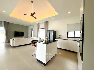 Modern open-layout kitchen and living room with sleek design and ceiling fan.