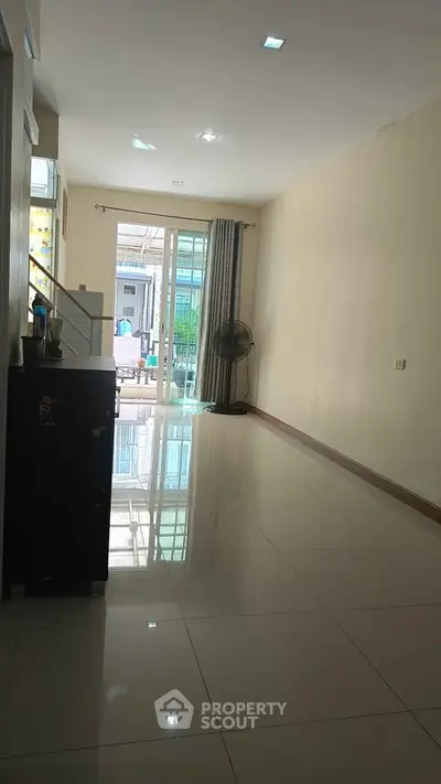 Spacious interior with glossy tiled flooring and large window for natural light.