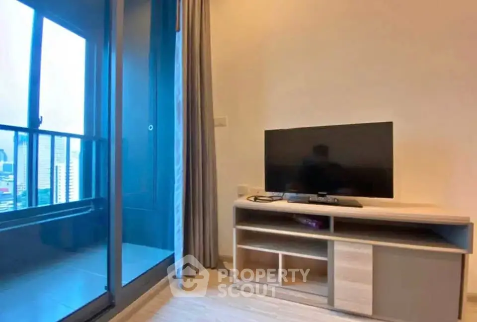 Modern living room with sleek TV setup and balcony view in urban apartment.