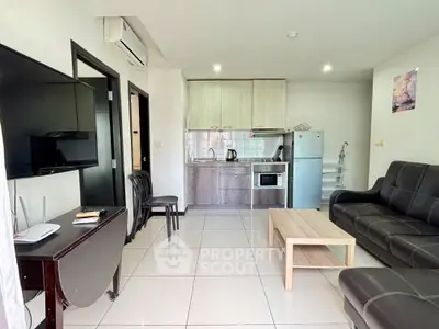 Modern living room with open kitchen, featuring sleek furniture and contemporary appliances.