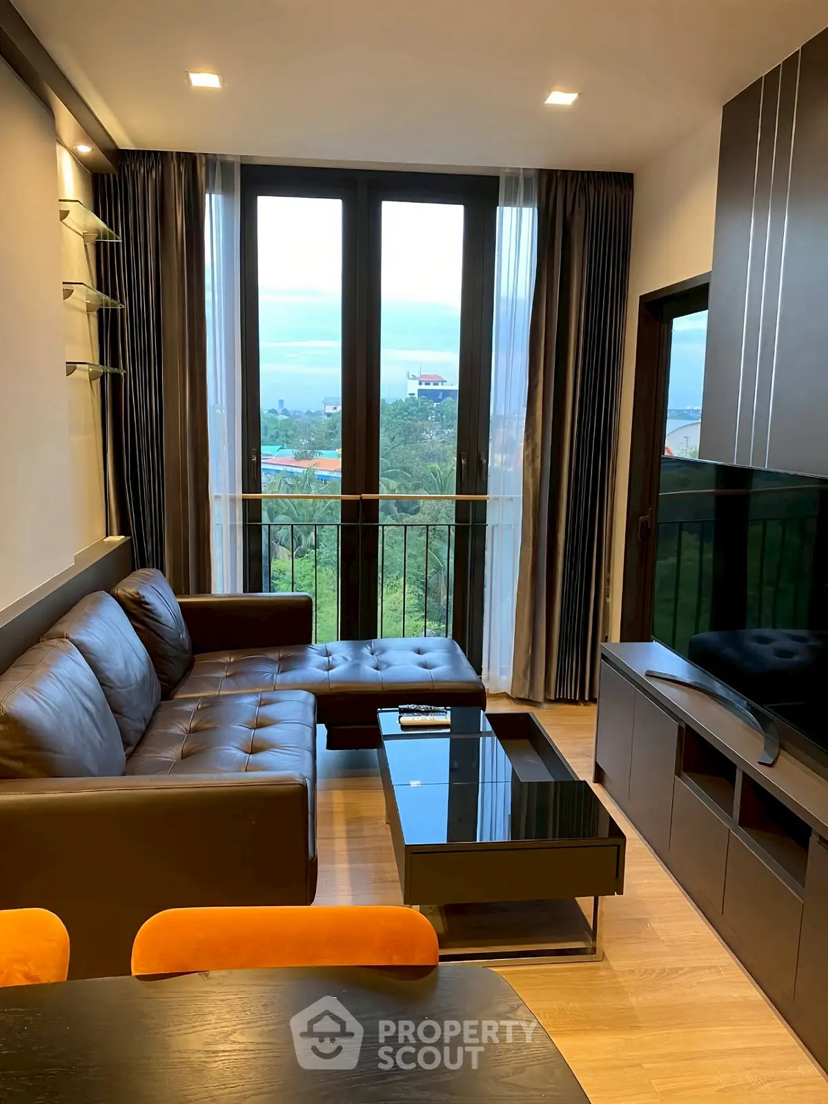 Modern living room with leather sofa, large windows, and scenic view