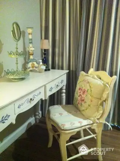 Charming vintage-style vanity area with elegant floral chair, classic white dressing table, and tasteful decorative items, perfect for a cozy bedroom corner.