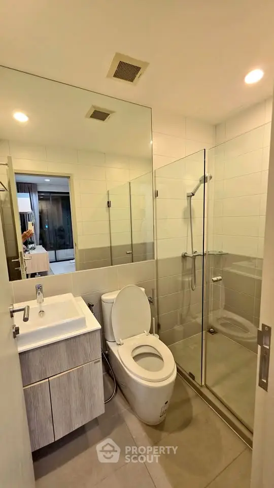 Modern bathroom with glass shower and sleek fixtures in contemporary apartment.