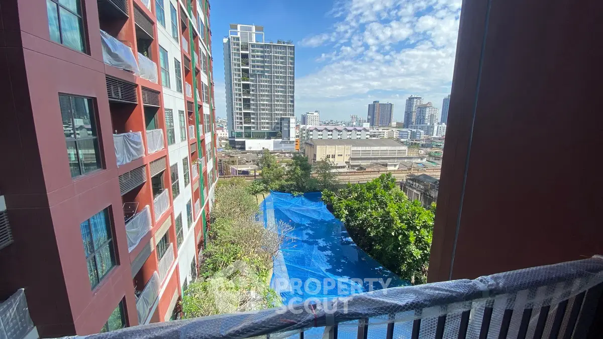Stunning urban view from a high-rise balcony overlooking cityscape and greenery.
